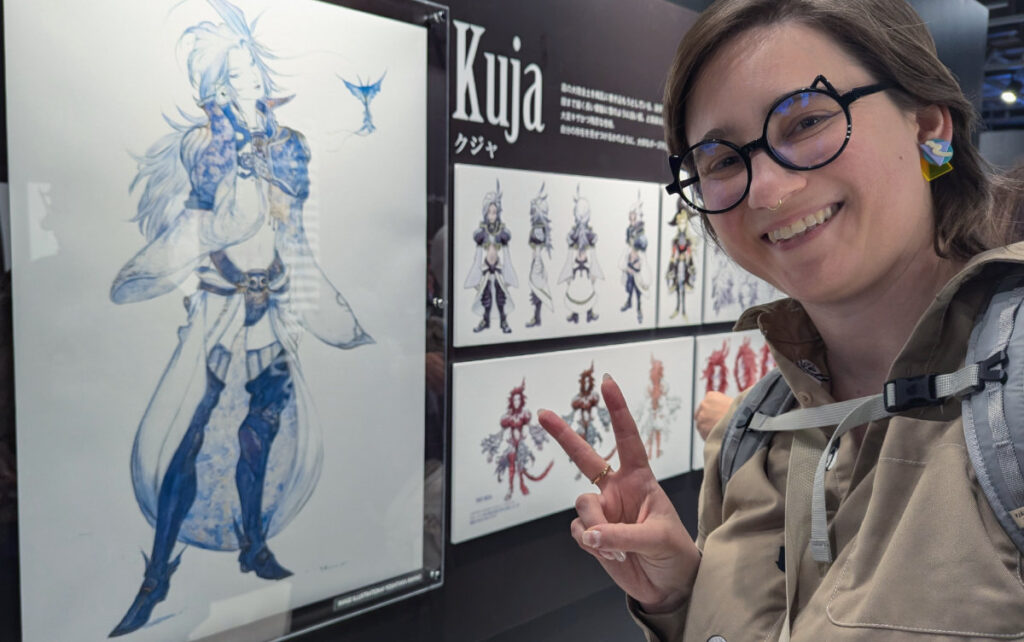 Selfie of me flashing the piece sign in front of concept art of my fav effeminite male villian, Kuja.