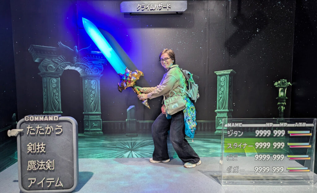 Me holding a replica FFIX sword. My knees are bent to make it look like the sword has some kind of weight to it. In front of me is a series of statues that make it look like the FFIX battle menu is surrounding me. The whole photo looks like it could be a battle scene from the game.